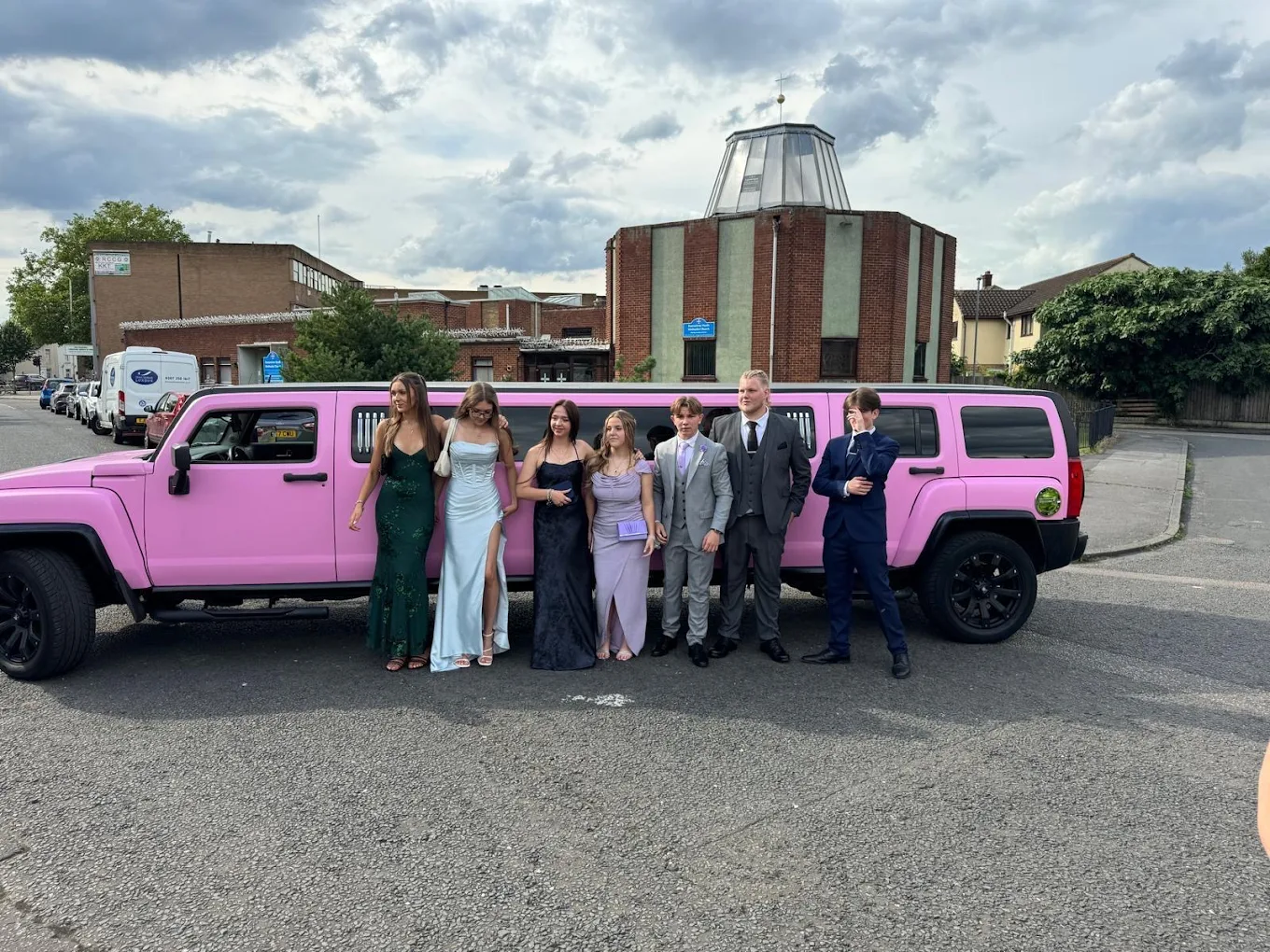 Prom group in dresses and suits arriving by stretch limousine